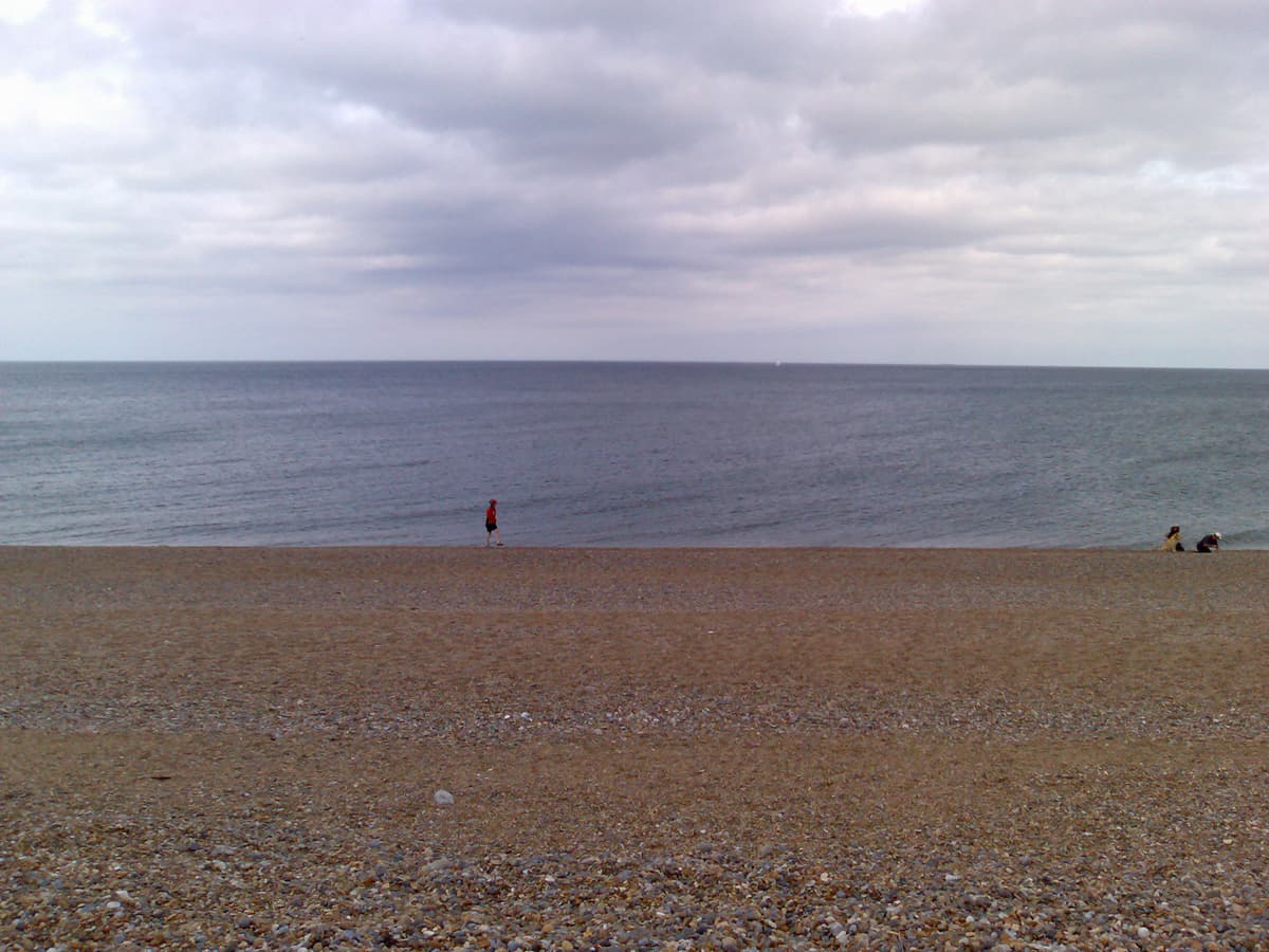 It was a much hillier part of Norfolk, and although we'd parked only about 10km away from Salthouses and we'd allowed about an hour to get there, we were lathered by the time we arrived.  In part because getting the bikes off the roof and set up took some time.  This photo is after the bottle of white wine and the lobster salad and the tiger prawn salad and is where we stroll along the beach.  As you can see, not crowded.<p>The two people and the labrador just along the beach from where Pippa is walking were fishing for mackerel.  Actually only the people were fishing the lab was just trying to eat them once caught.
