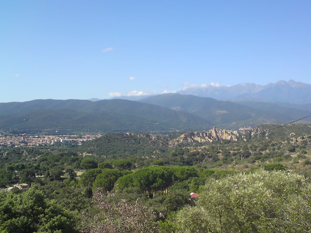 <p>9.52am  There was the most fantastic eroded rock formation just to the right of the town as I descended.  Click to see it in more detail.  I'd stopped to take this photo and the buzz of cicadas filled the thyme scented air - and the air was just so warm as my bike swooshed down the curves - warm with those occasional cold bits where there is a sudden scent of cold, wet leaves and pine as you go between trees.  Ah, perfect.</p>
